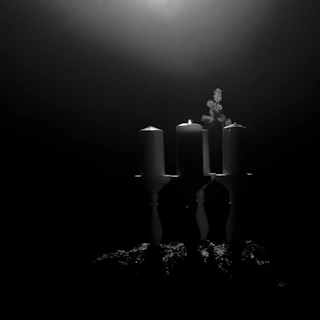 A set of three colorful candles arranged artfully on a stone surface with soft natural light.