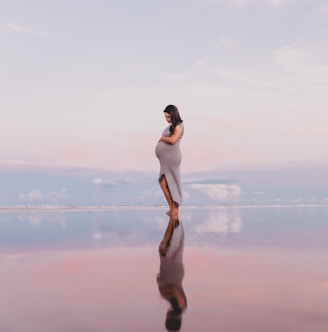 pregnant woman standing on calm body of water