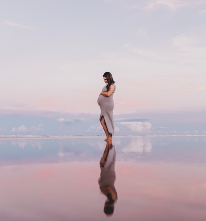 pregnant woman standing on calm body of water