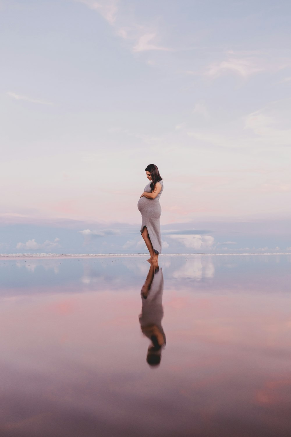 pregnant woman standing on calm body of water