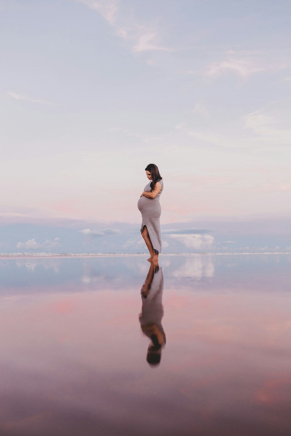 mujer embarazada de pie sobre un cuerpo de agua tranquilo