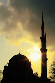A peaceful mosque silhouette at sunset with soft golden light.