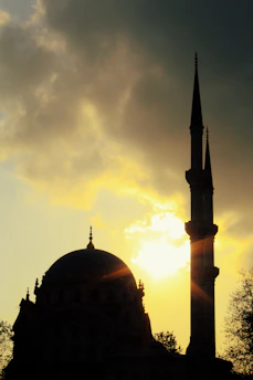 A serene mosque silhouette at sunset with soft golden light.