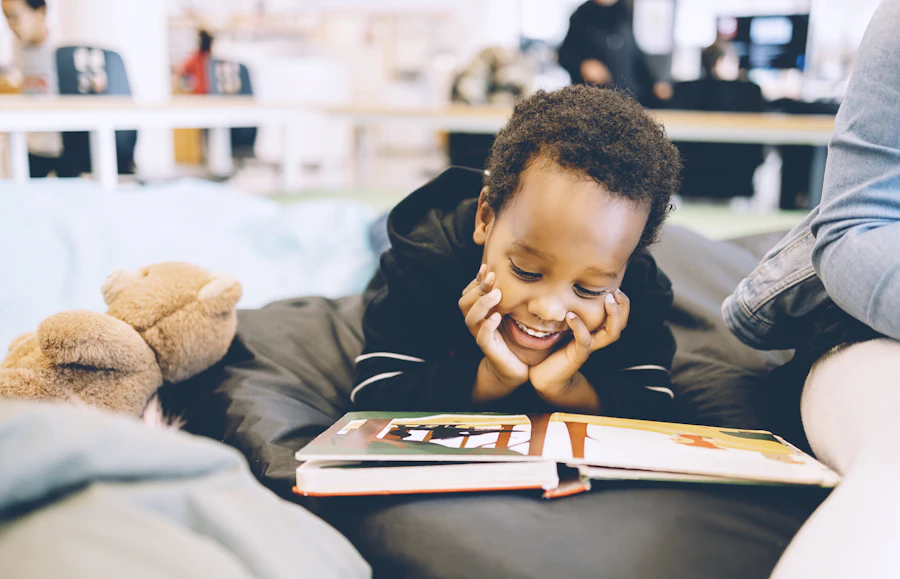 A boy smiling while reading a book.