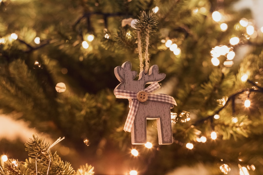 selective focus photo of brown deer ornament on Christmas tree with turned-on string lights