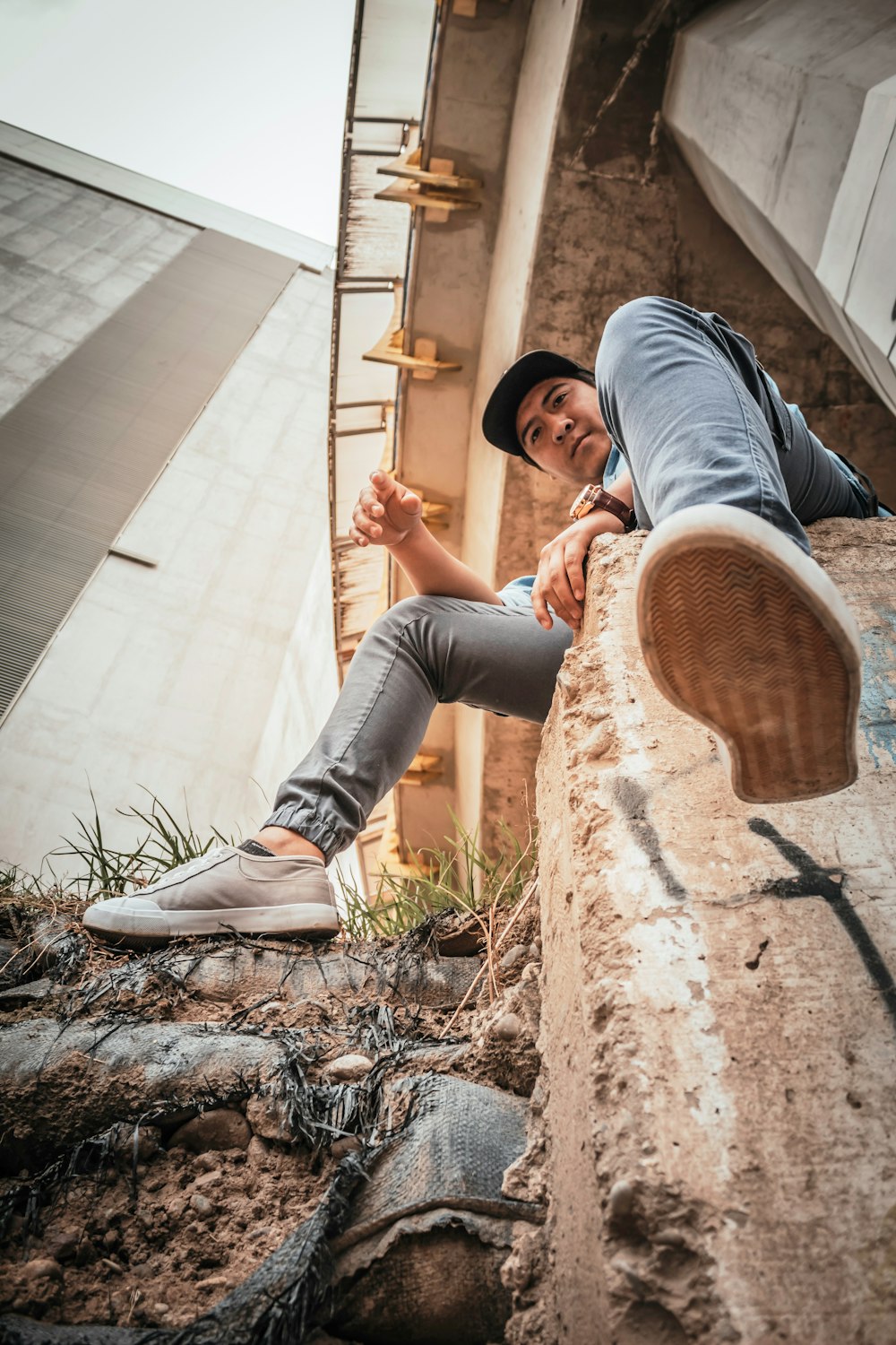 man sitting on concrete fence near house