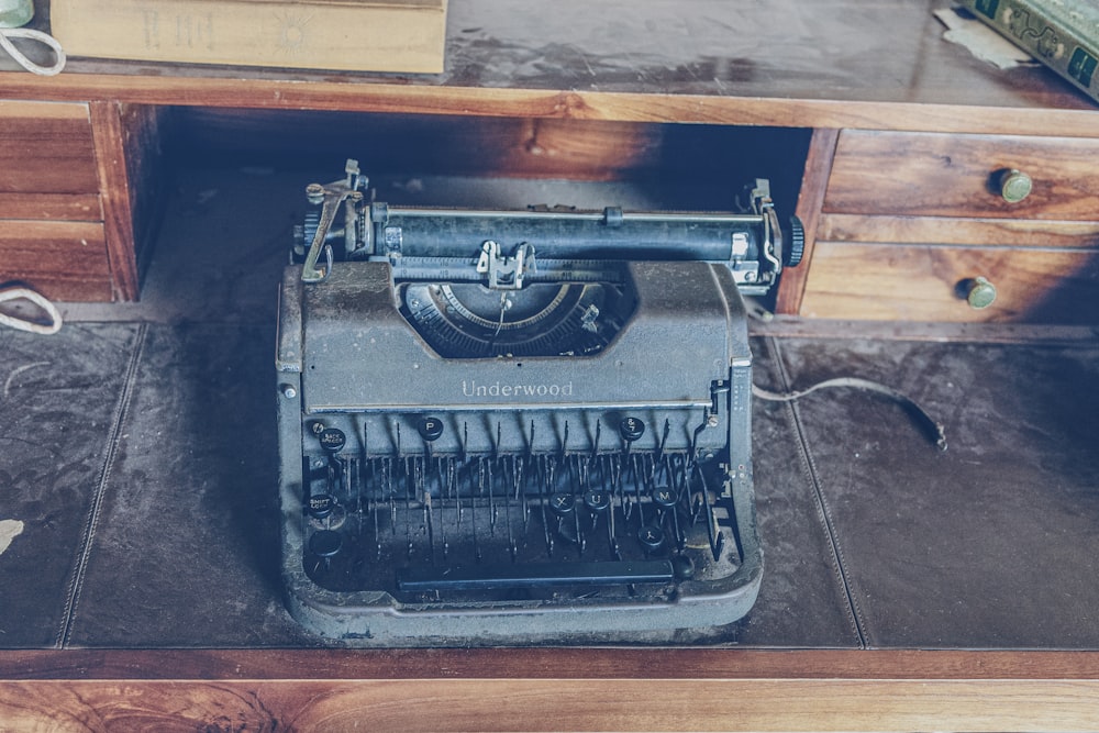 vintage gray typewriter on black and brown wooden desk