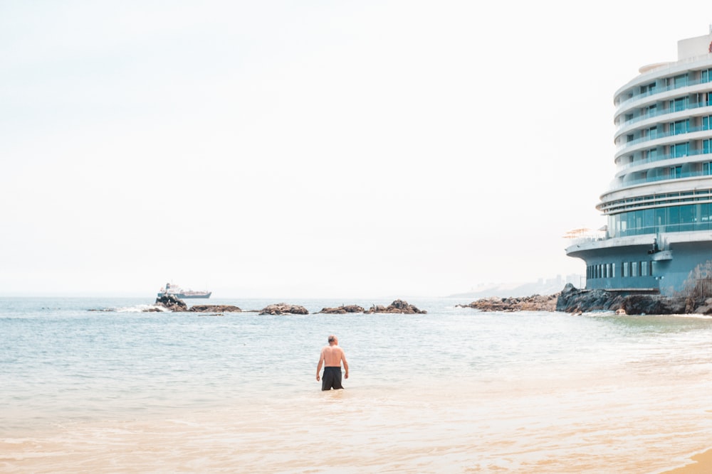 a man standing in the ocean next to a hotel