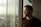 man leaning on the post of the window