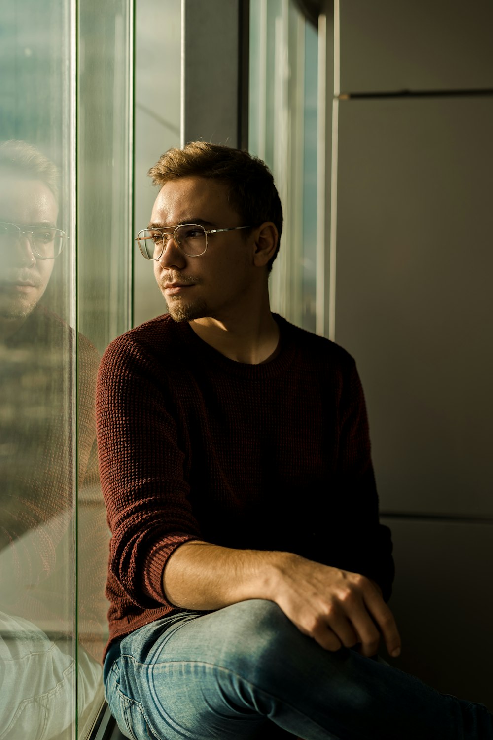 man sitting near glass wall