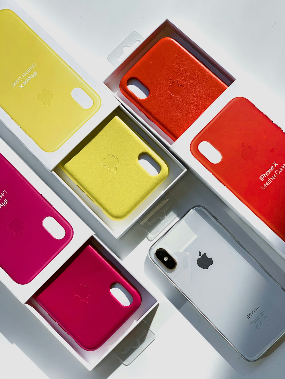 silver iPhone X with assorted-color cases with boxes
