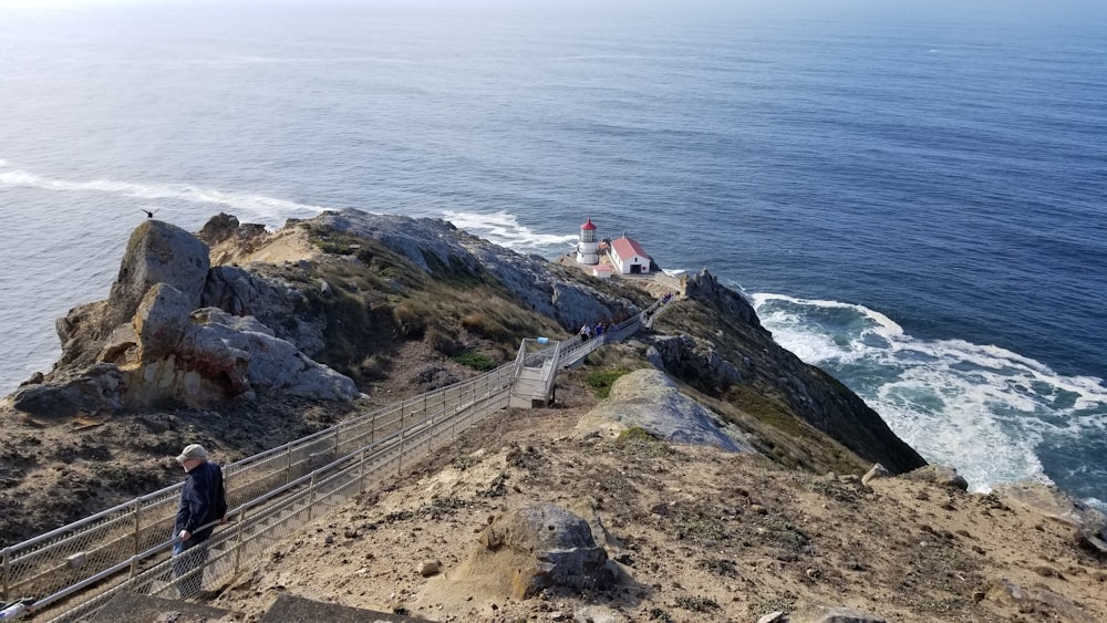 person leaning on metal fence on sea cliff