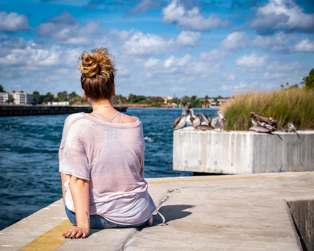 woman wearing grey shirt sitting on grey concrete surface