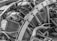The image features an intricate view of a mechanical engine, showcasing various metal components, pipes, and bolts. The arrangement and complexity of the parts suggest a heavy-duty machine or vehicle engine. The texture and details of the metal surfaces are highlighted in black and white, emphasizing the industrial nature of the image.