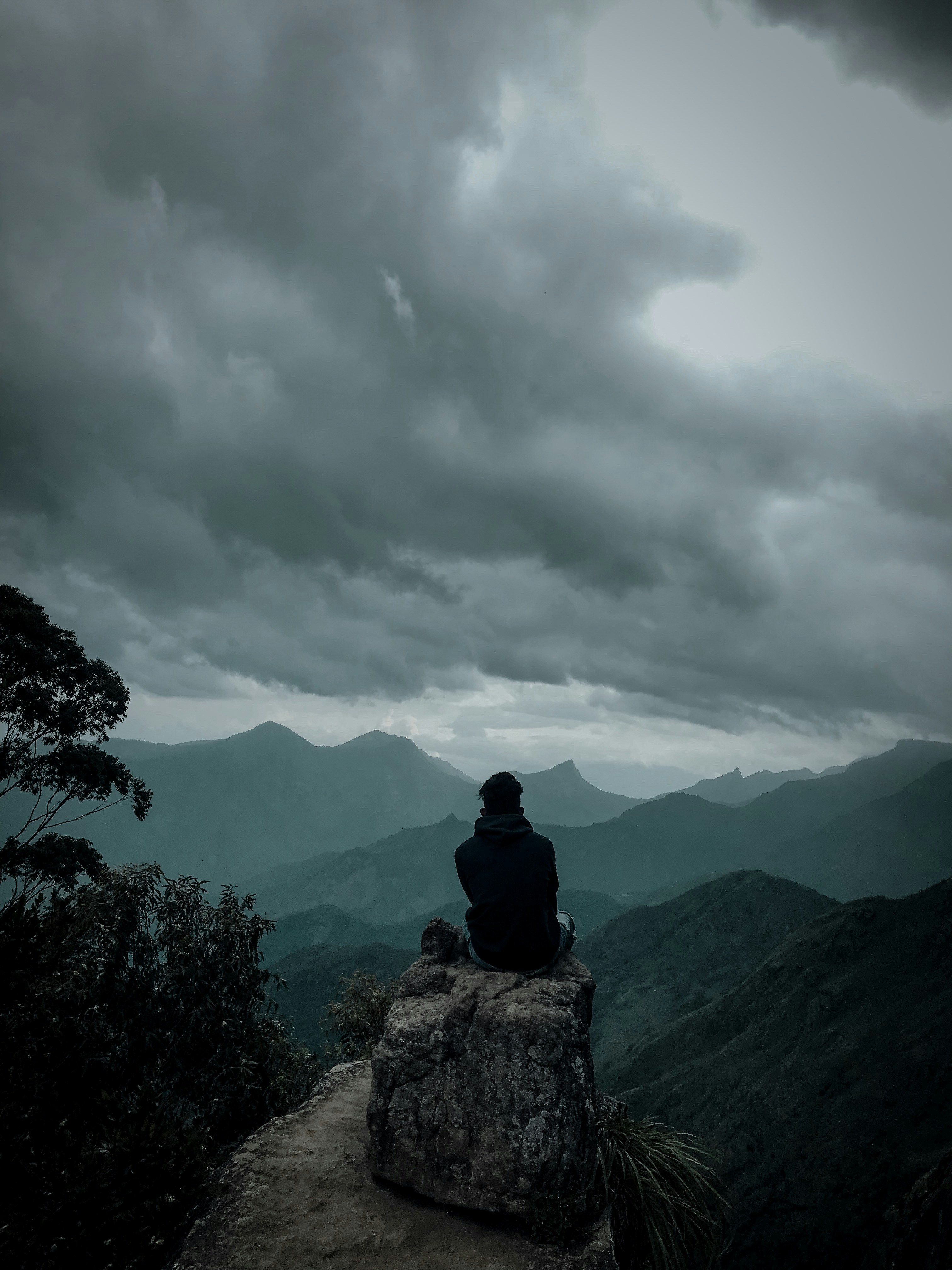 man sitting on gray boulder