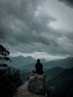 man sitting on gray boulder
