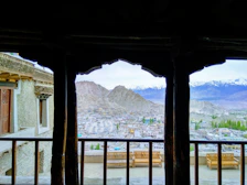 Sunlit balcony with a view of the mountains and local village rooftops.