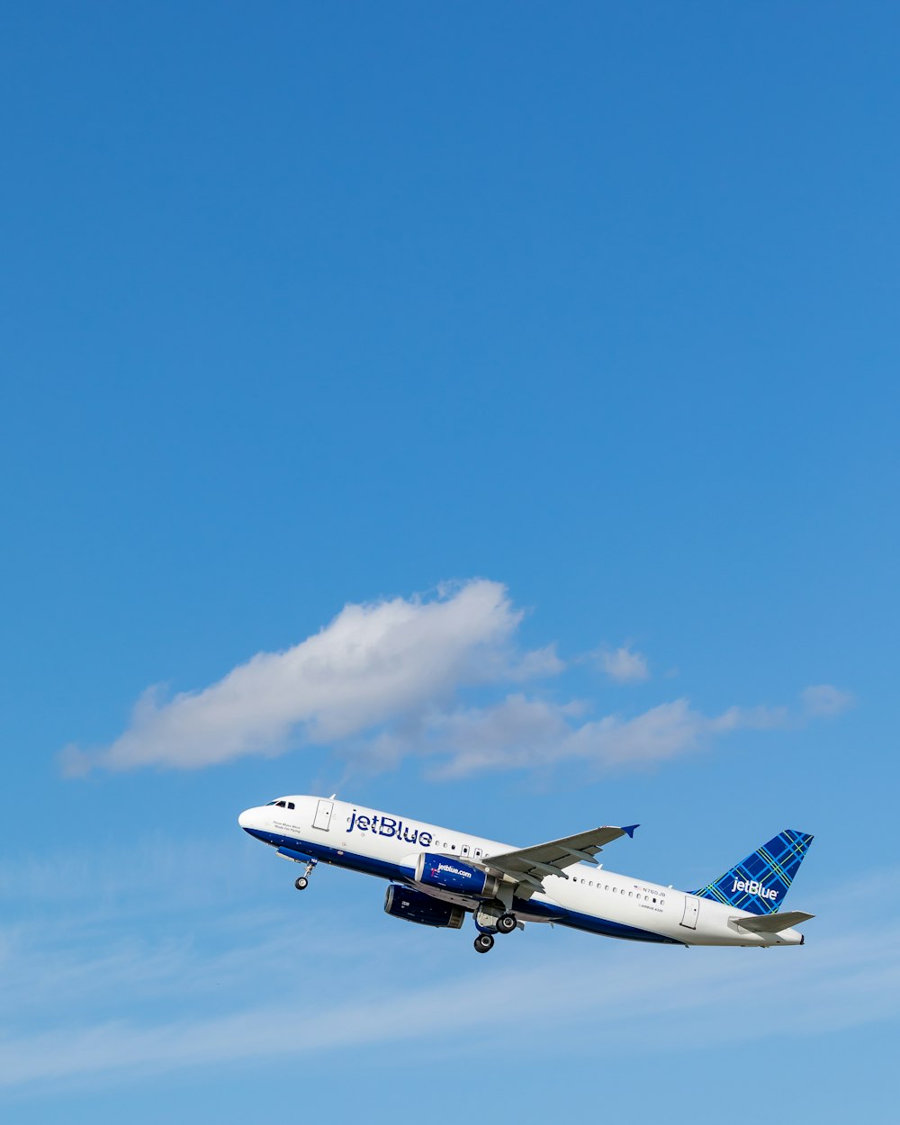 avión de pasajeros Jetblue blanco y azul volando en el cielo
