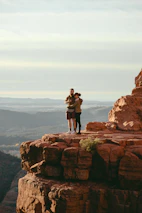 Clara and Owen standing on a rocky trail overlooking the vast Colorado mountain landscape.