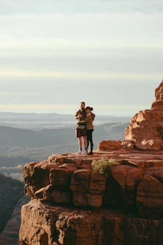 Clara and Owen standing on a rocky trail overlooking the vast Colorado mountain landscape.