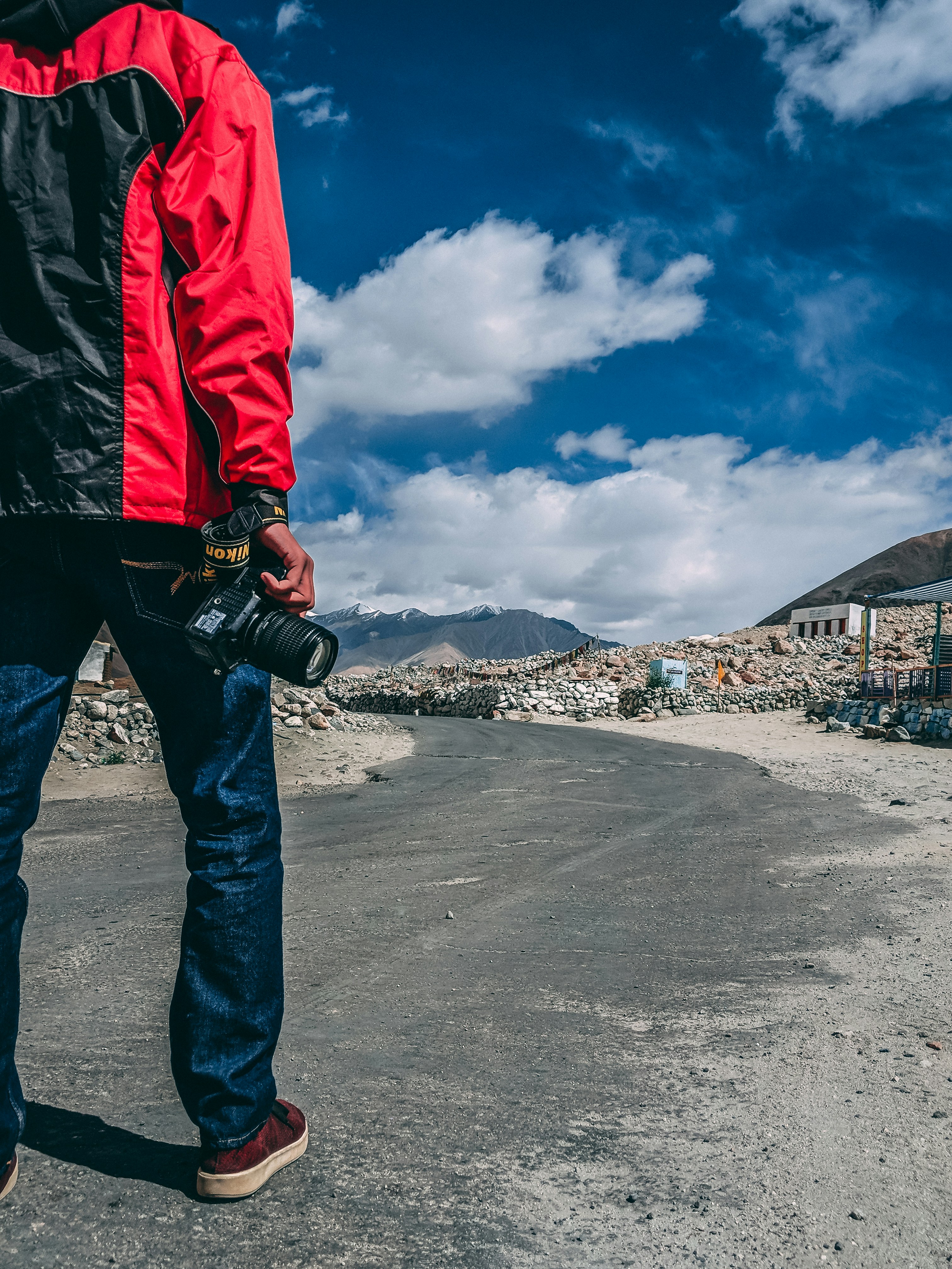 man walking on roadway while holding DSLR camera
