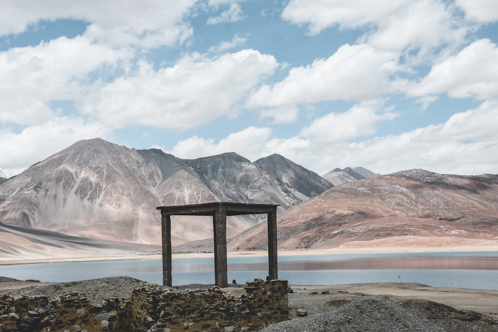 square grey wooden gazebo beside body of water during daytime