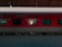 A red train carriage is stationary at a platform, under a canopy. The windows reveal the interior of the A.C. 3 tier sleeper car, and some text is visible on the exterior. The platform is empty and the train appears ready for boarding.