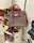 A gray and pink handbag displayed on a clear chair is surrounded by a variety of plush toys and a collection of books, including a visible 'Aladdin' book. In the background, there are vibrant flowers and artwork featuring abstract line drawings and text.