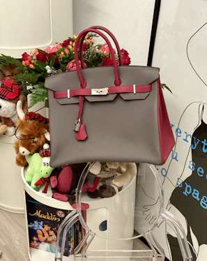 A tote bag with playful prints hanging on a hook beside a small pile of colorful children’s books.