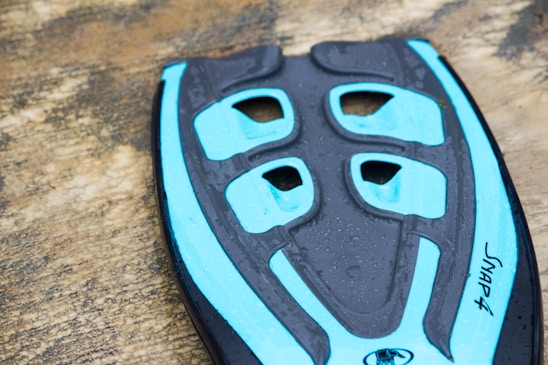 Close-up of a sleek aetherion Zeropoint paddle resting on a dark obsidian surface with electric cyan highlights.