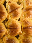 Golden flaky croissants stacked neatly on a white plate.