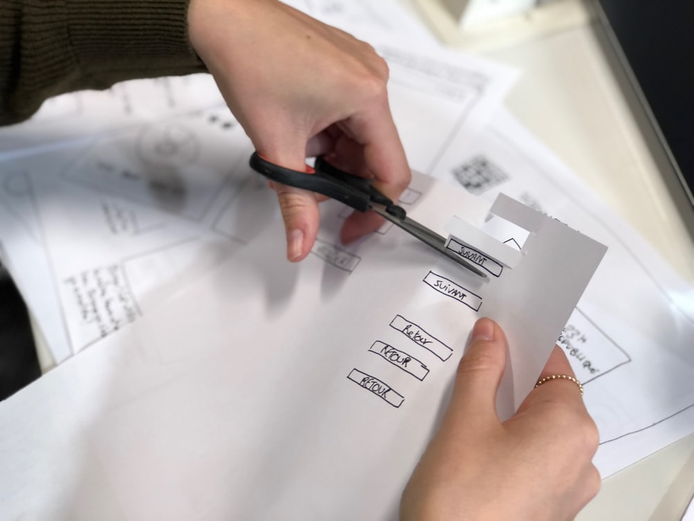 person holding scissors while cutting paper