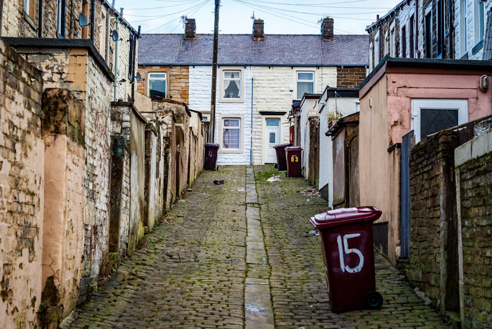 trash bins near wall beside houses