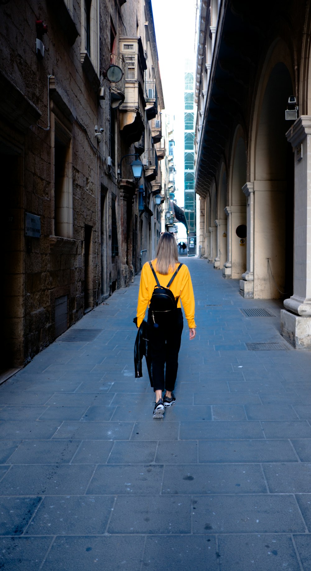 woman walking between buildings during daytime