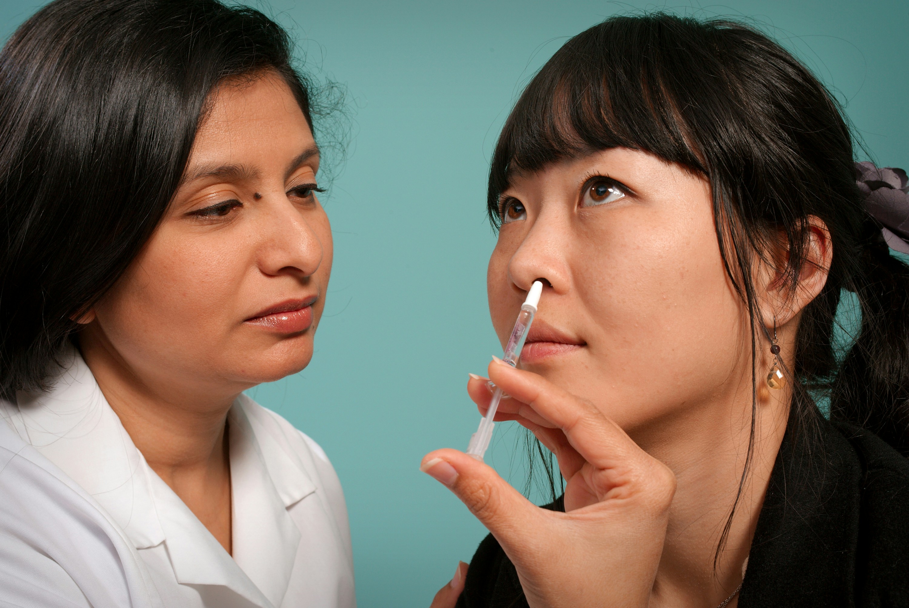 &quot;This 2009 image depicts a healthcare practitioner as she was administering the H1N1 live attenuated intranasal vaccine (LAIV) to an Asian woman. Using a small syringe, she was delivering the vaccine mist into the woman\u2019s left nostril. Photographer Jame Gathany&quot;