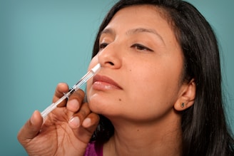 a woman is putting a sy in her nose