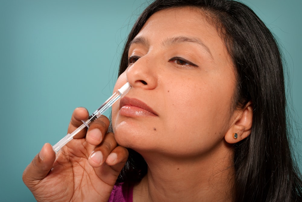 Eine Frau steckt sich einen Sy in die Nase