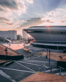 few people walking near buildings and stadium under blue and brown sky