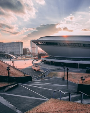 few people walking near buildings and stadium under blue and brown sky