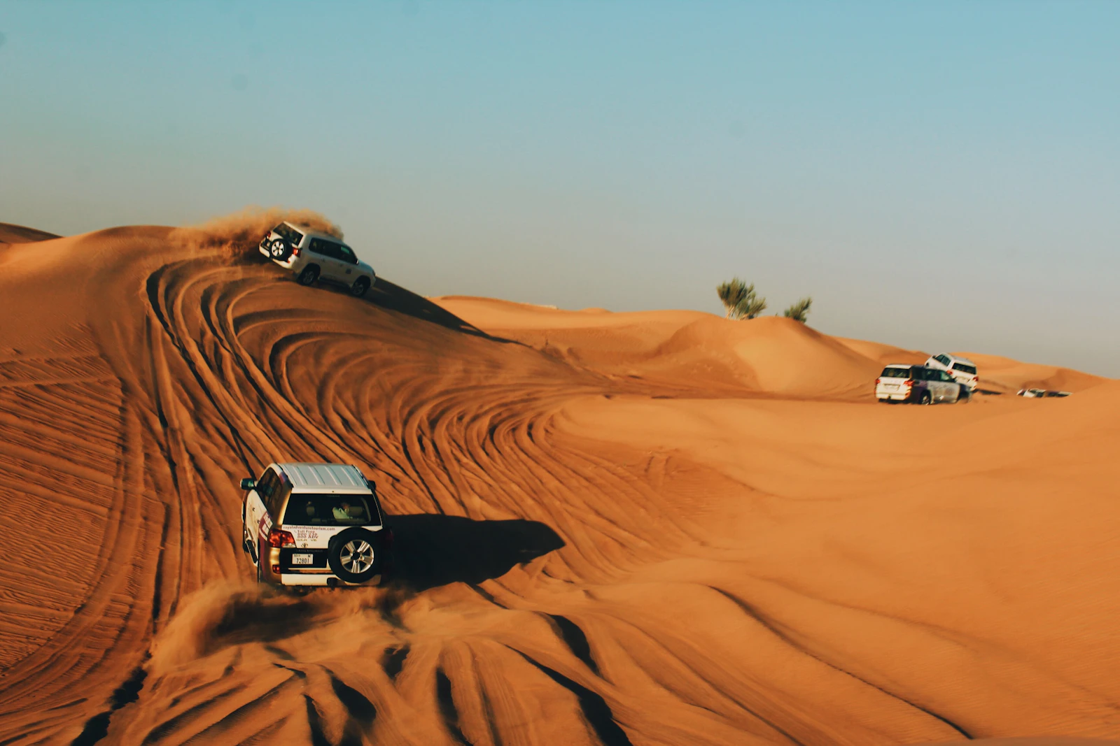 4x4 vehicles dune bashing across golden Dubai dunes