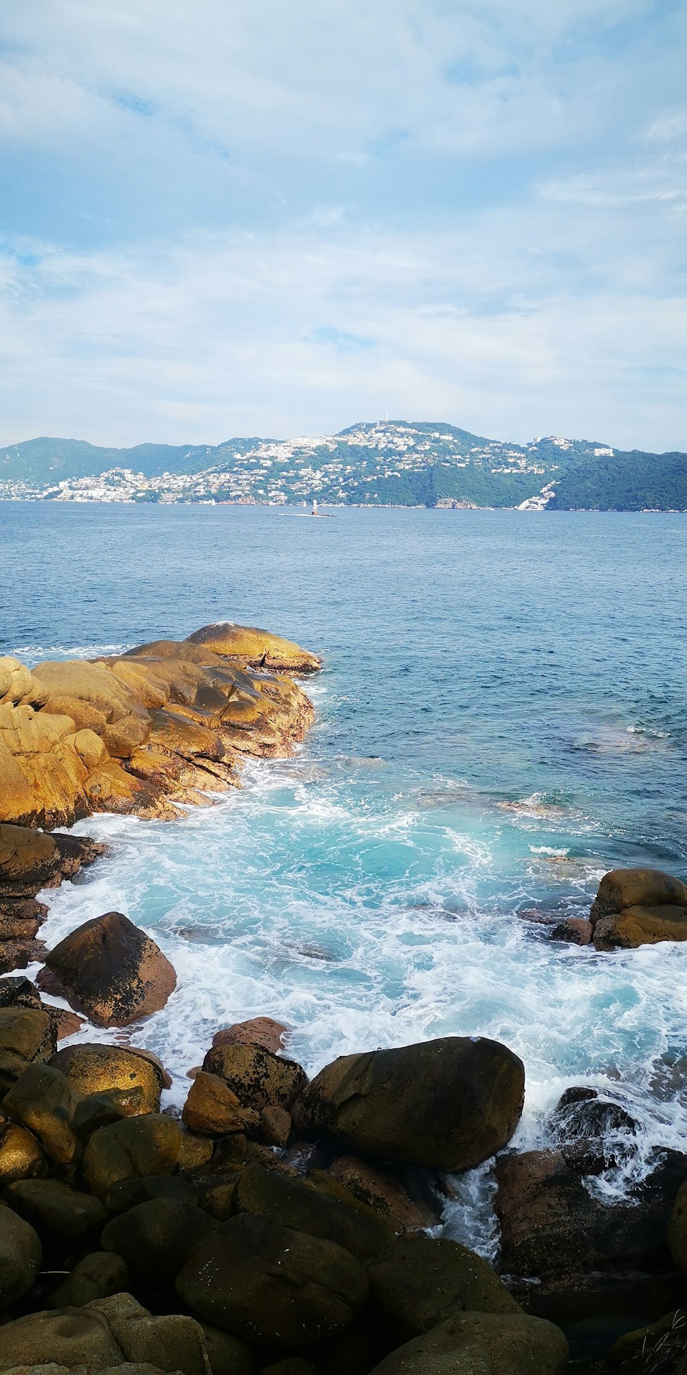 fotografia aerea di formazioni rocciose vicino allo specchio d'acqua sotto il cielo blu e bianco