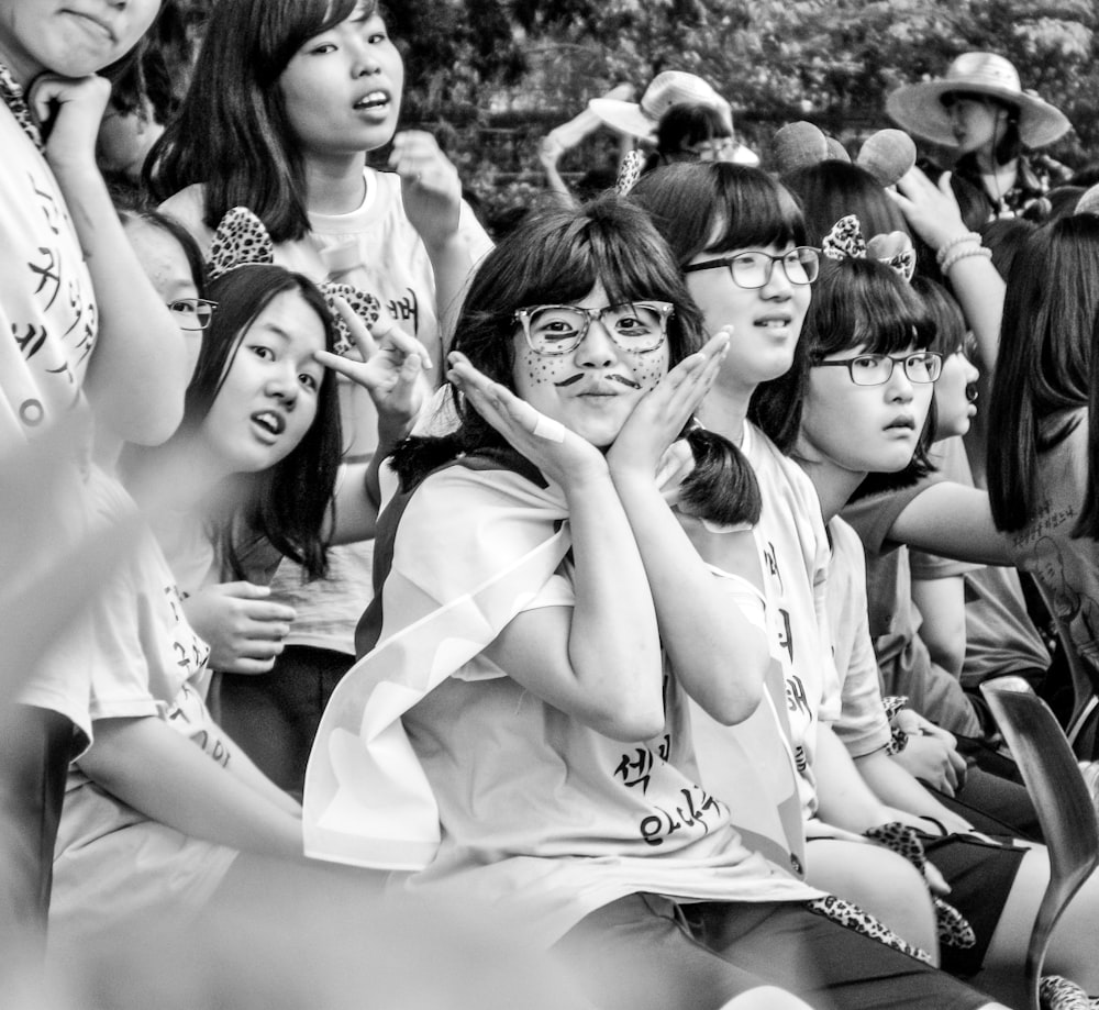 grayscale photography of group of women sitting and others are standing