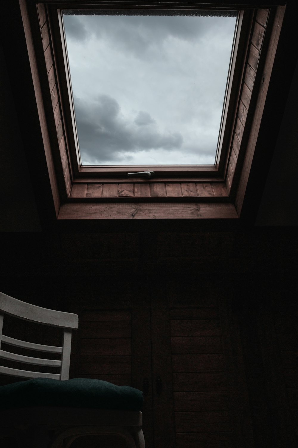 vacant white and green padded armless chair viewing ceiling under white and gray sky