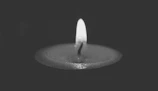 Serene scene of a single candle glowing softly on a charcoal textured surface