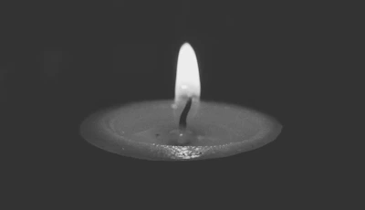 Serene scene of a single candle glowing softly on a charcoal textured surface