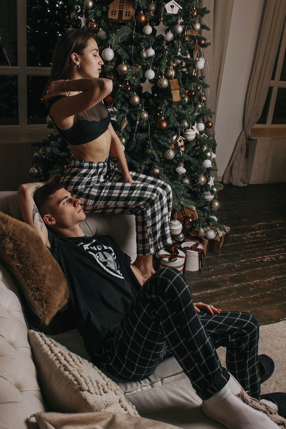 a man and a woman sitting on a couch in front of a christmas tree