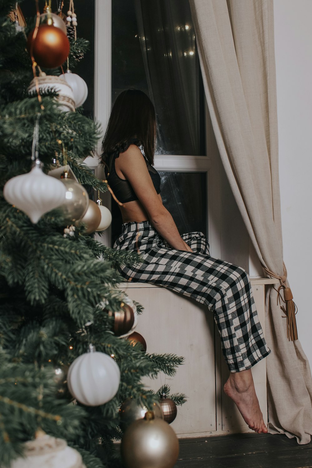 woman sitting on gray wooden cabinet beside window