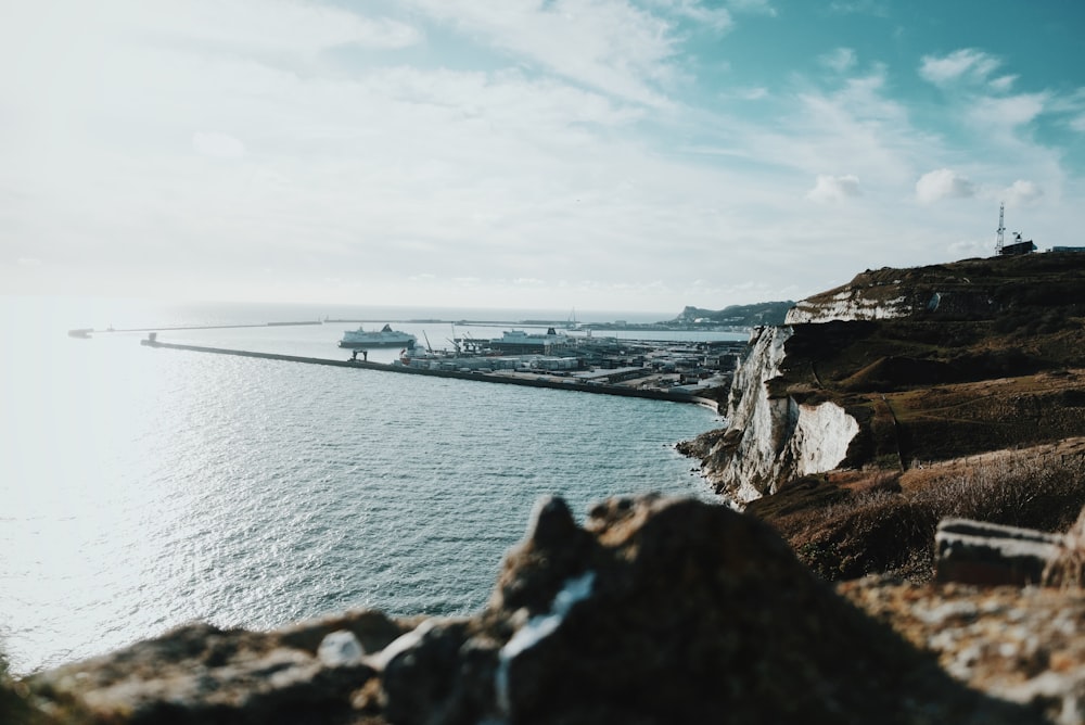 brown cliff near sea under cloudy sky