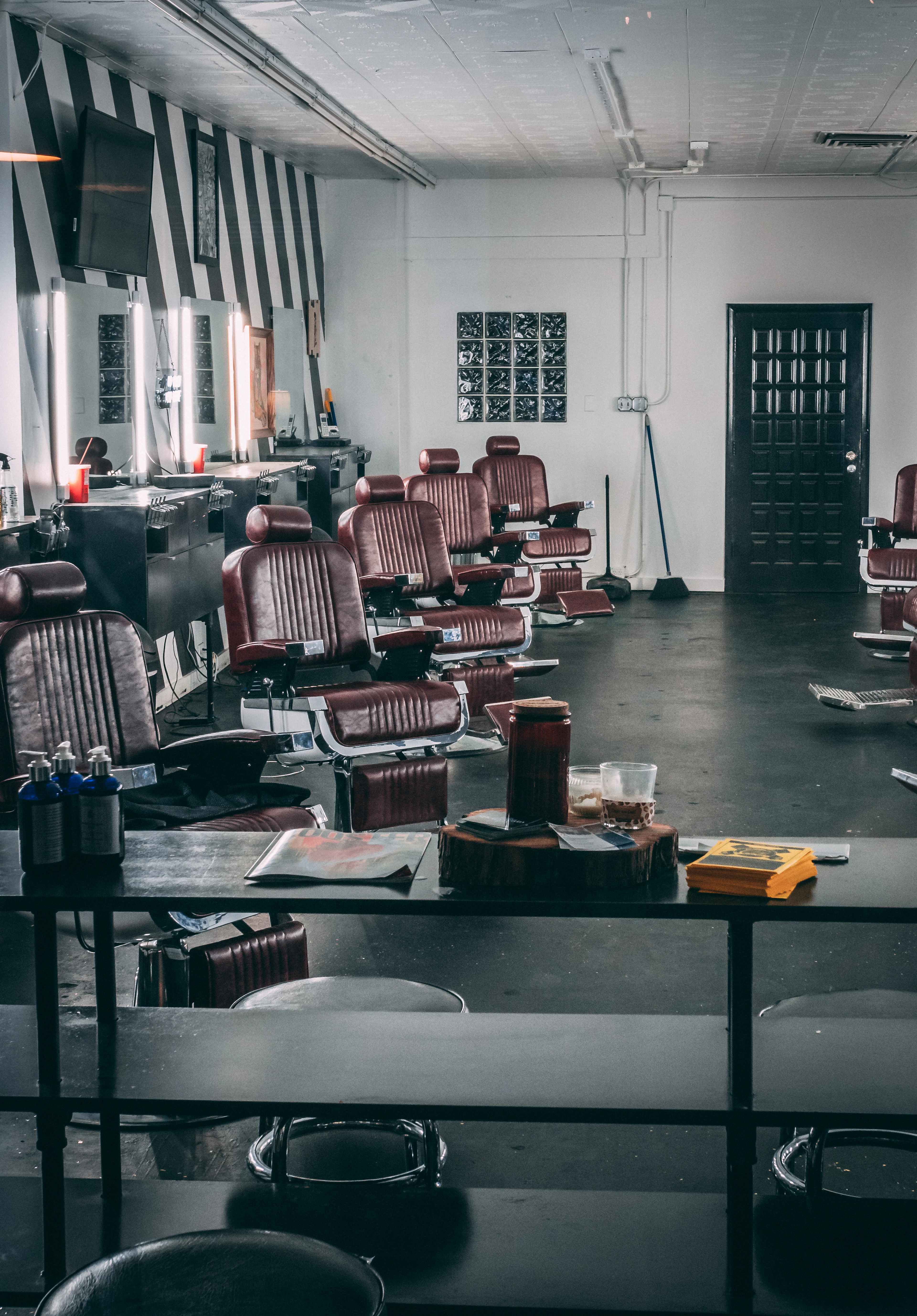 A row of brown leather barber chairs facing mirrors in a warm-lit shop