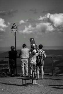 grayscale photography of four person standing while looking on mountain ranges